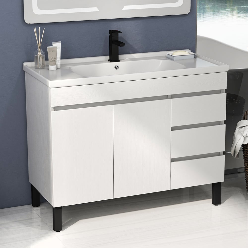 Bathroom vanity with white countertop, black faucet, and cabinets against a blue wall.