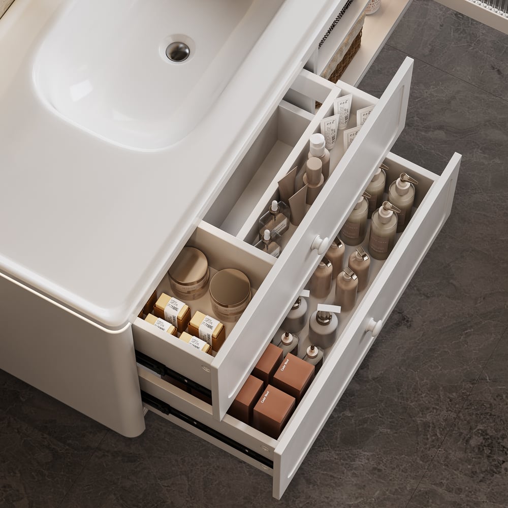 Open drawer under a bathroom sink with toiletries on a dark tiled floor.