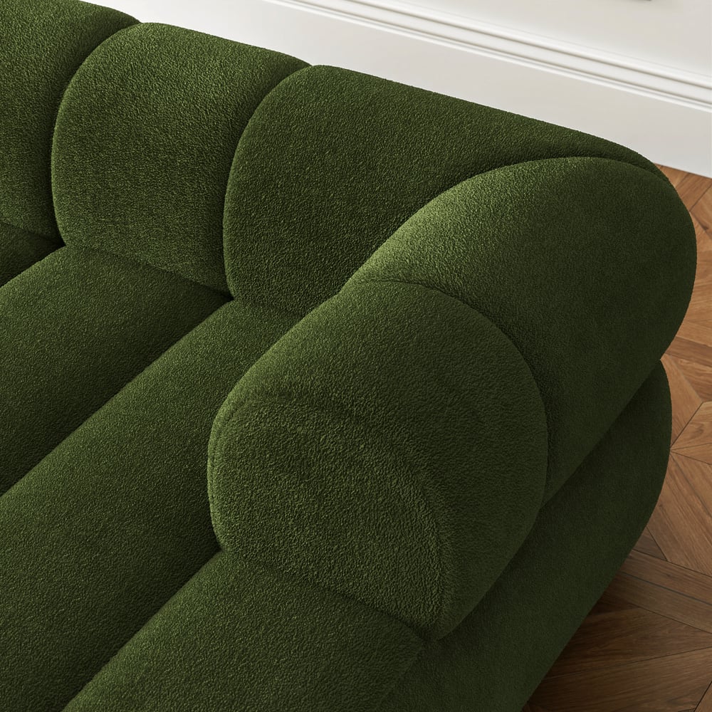 Green upholstered chair on a wooden floor with white baseboard.