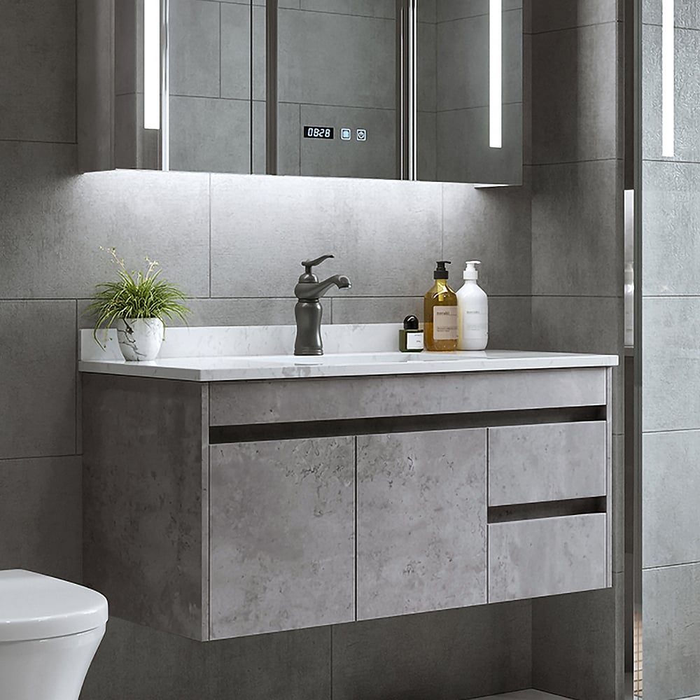 Bathroom vanity with sink, faucet, and decorative items against a tiled wall.