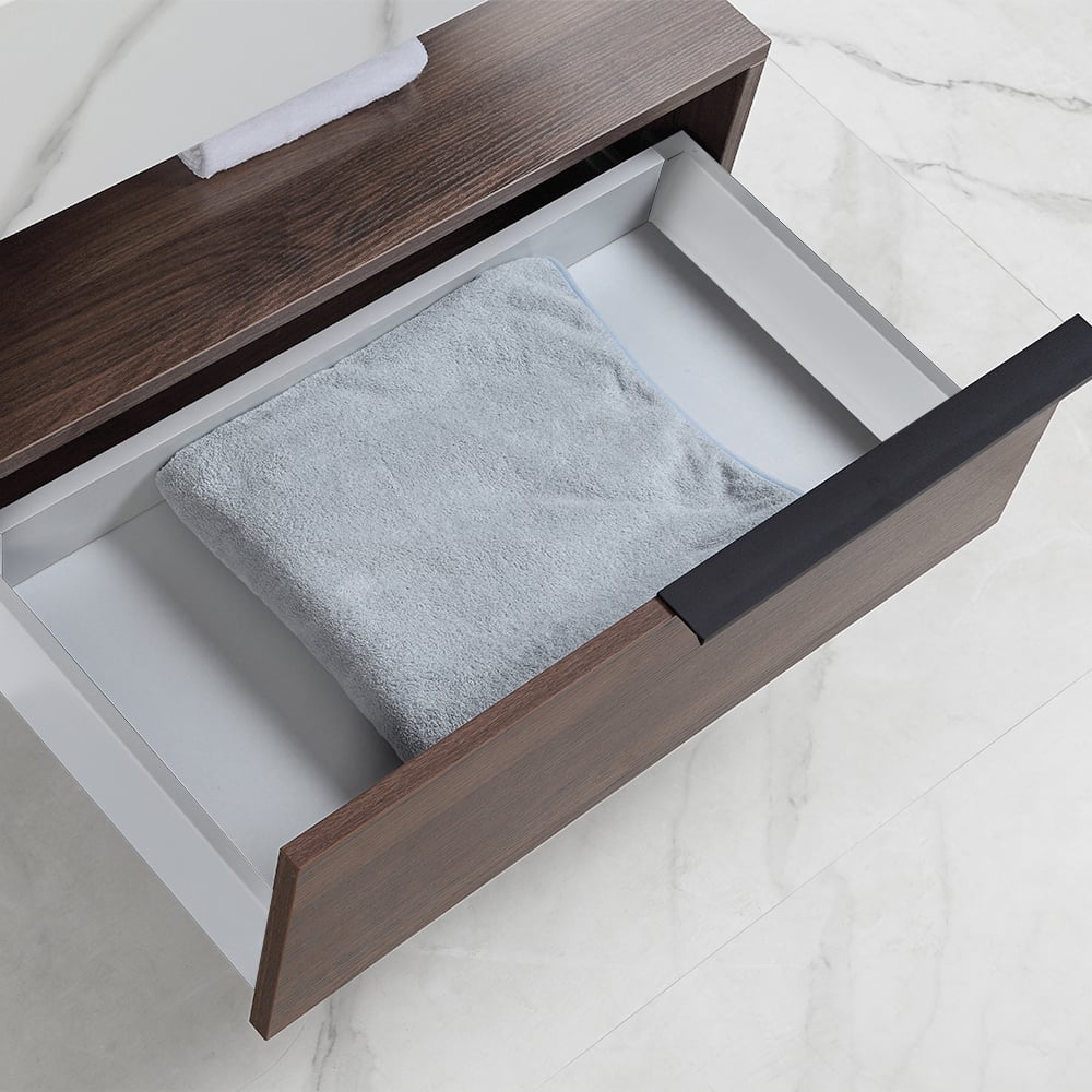 Open drawer with a gray towel inside, on a white marble surface.