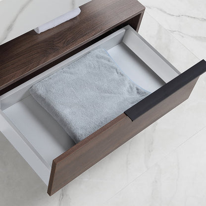 Open drawer with a gray towel inside, on a white marble surface.