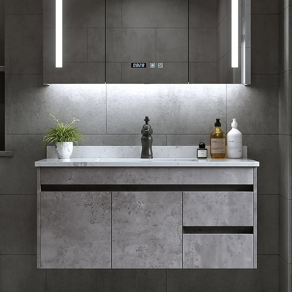 Bathroom vanity with marble countertop and decorative items against a tiled wall.