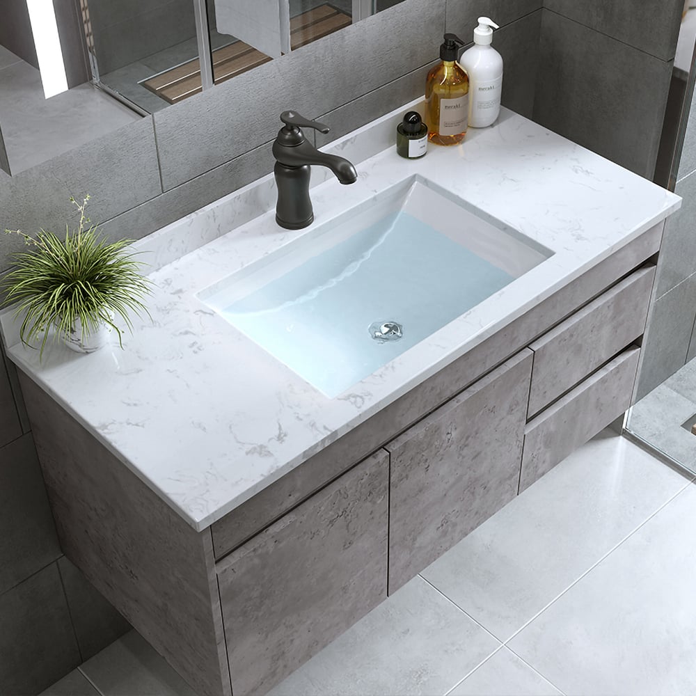Bathroom vanity with sink, faucet, and toiletries on a light gray countertop.