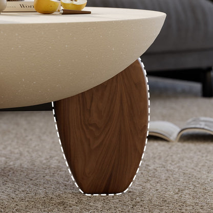 Close-up of a coffee table with a wooden leg on a carpeted floor.