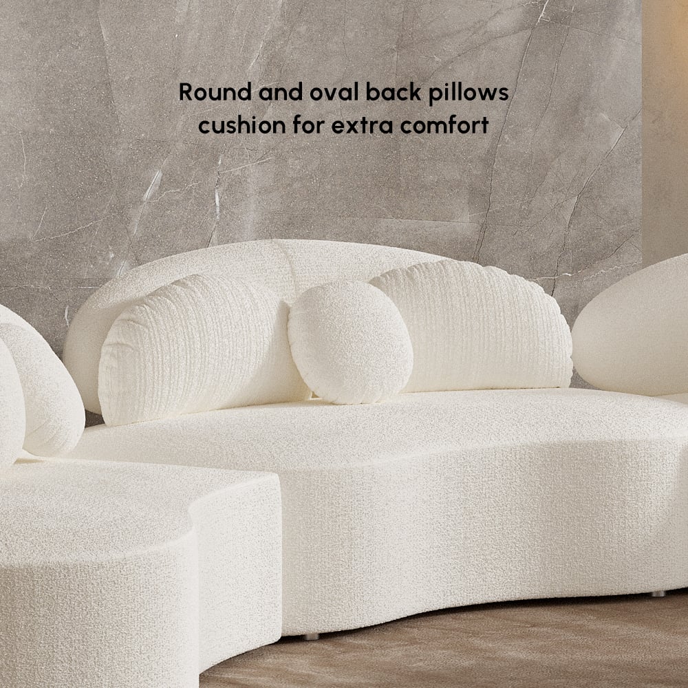 White sofa with round and oval back pillows on a neutral background