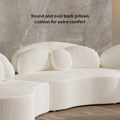 White sofa with round and oval back pillows on a neutral background