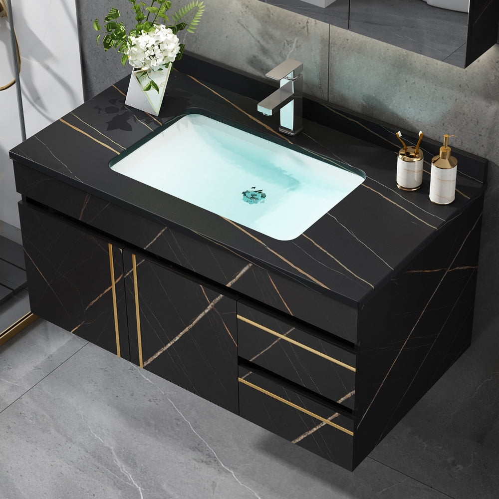Bathroom vanity with black marble finish, white sink, and decorative items.