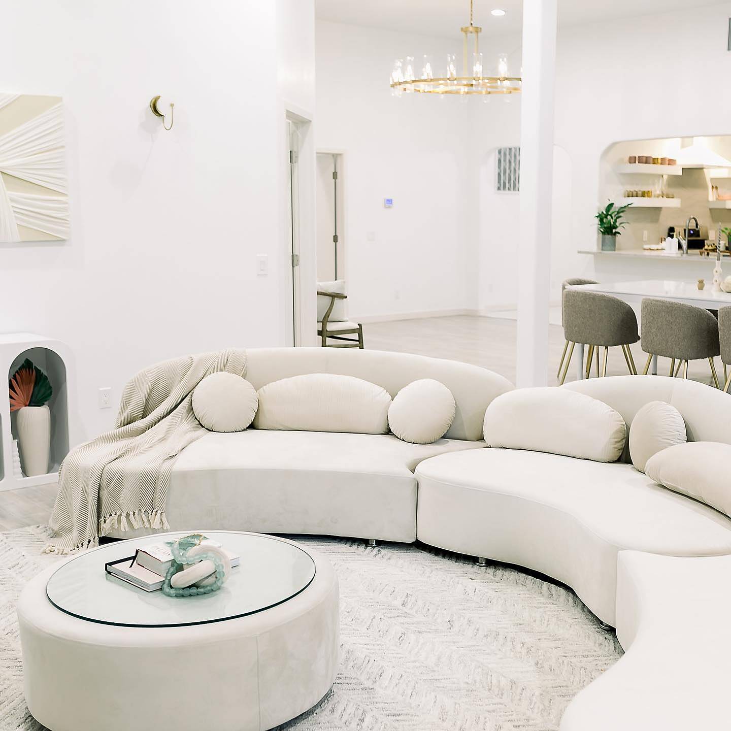 Modern living room with a curved white sofa and round coffee table.