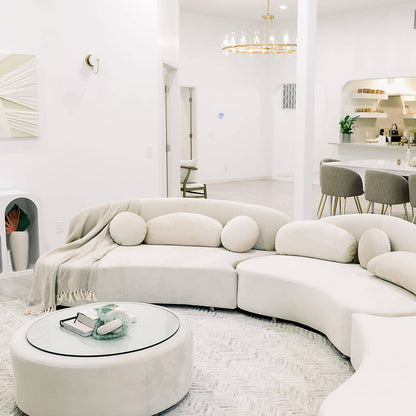 Modern living room with a curved white sofa and round coffee table.
