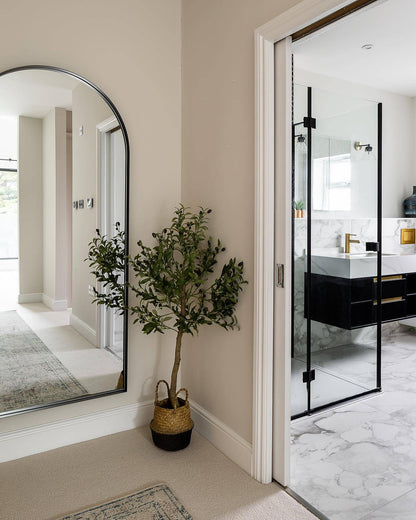 Bathroom interior with a plant, large mirror, and glass-enclosed shower.