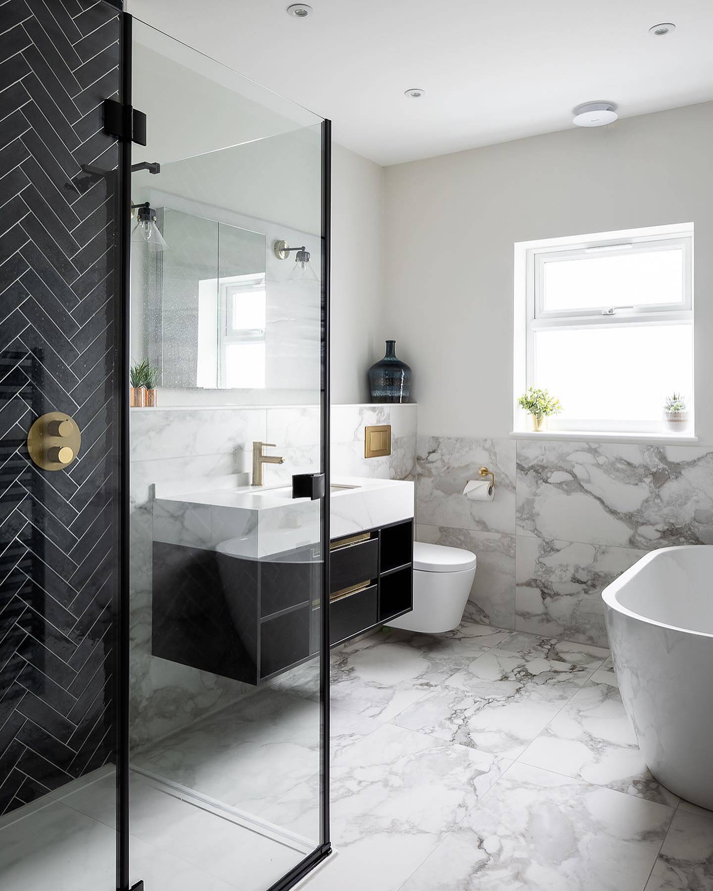 Modern bathroom with black and white design elements, including a freestanding bathtub and glass shower enclosure.