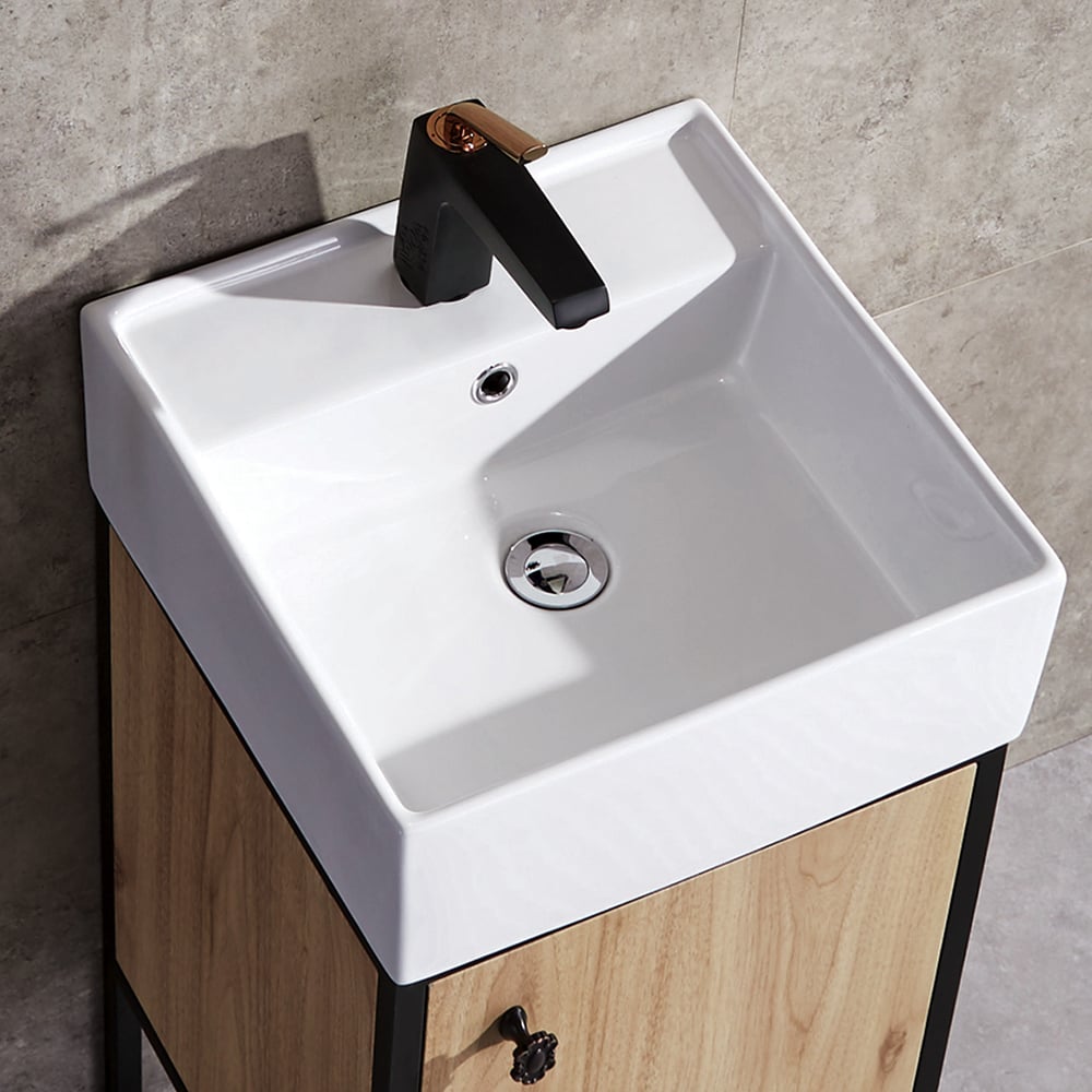 White sink with black faucet on a wooden cabinet against a gray tiled wall.