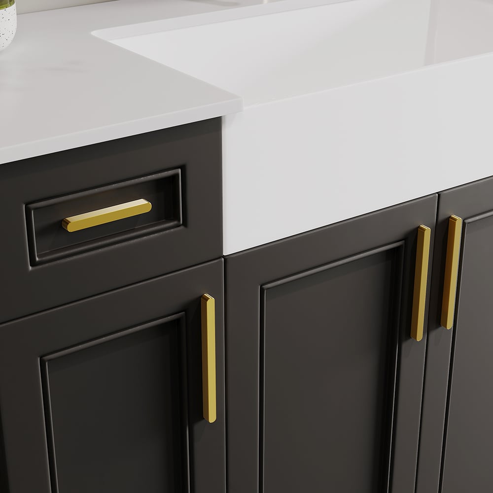 Gray kitchen cabinets with gold handles on a white countertop.