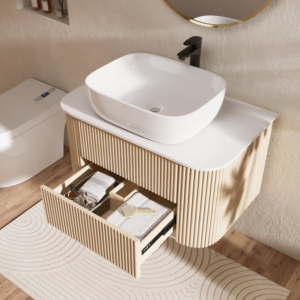 Bathroom vanity with white sink and open drawer, featuring towels and a key.