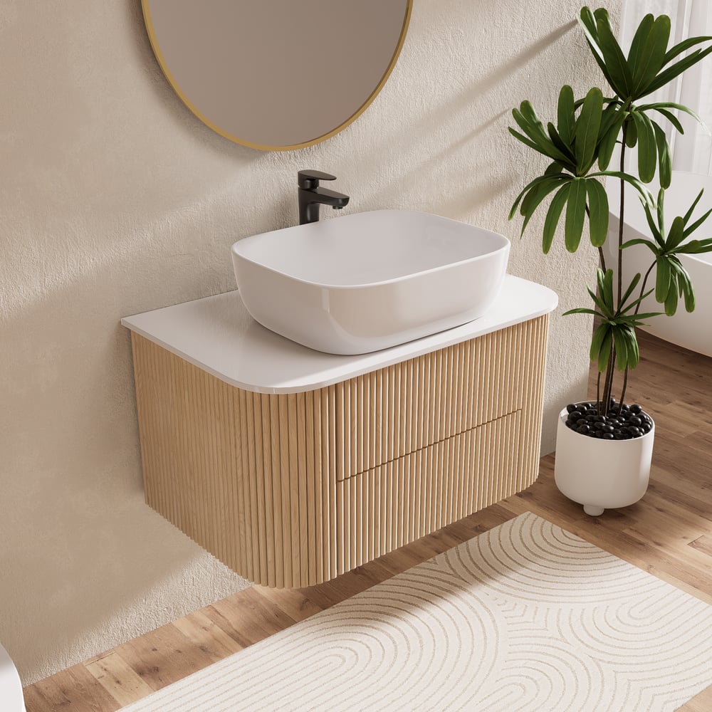 Bathroom vanity with white sink, wooden cabinet, and plant on a wooden floor.