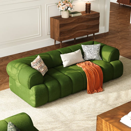 Green sofa with decorative pillows and a blanket in a living room setting.