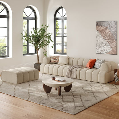 Modern living room with a beige sofa, ottoman, and coffee table.
