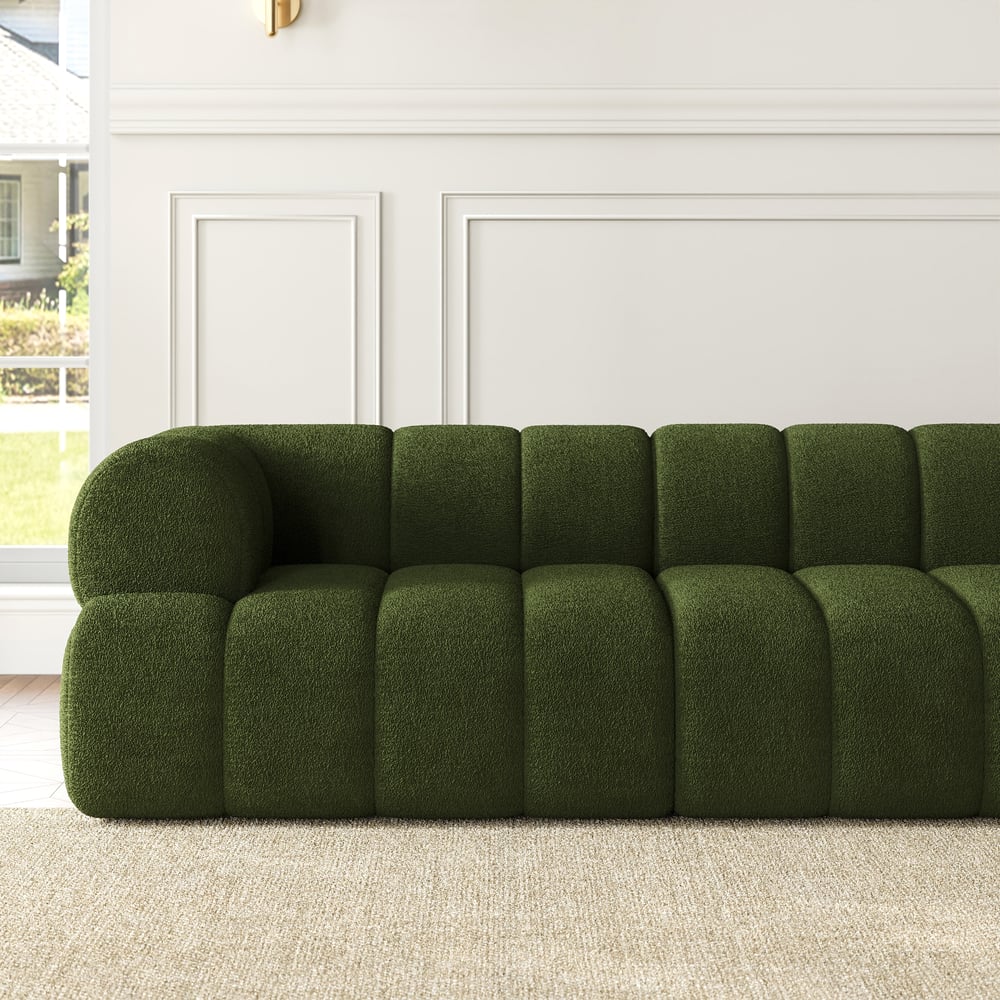 Green sofa in a living room with white walls and a window.