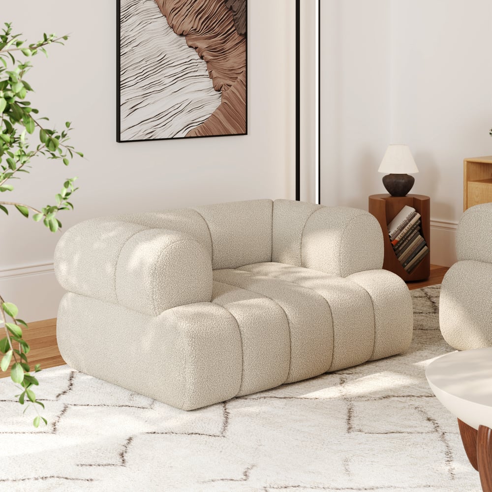 Beige armchair in a modern living room with a plant and framed artwork.