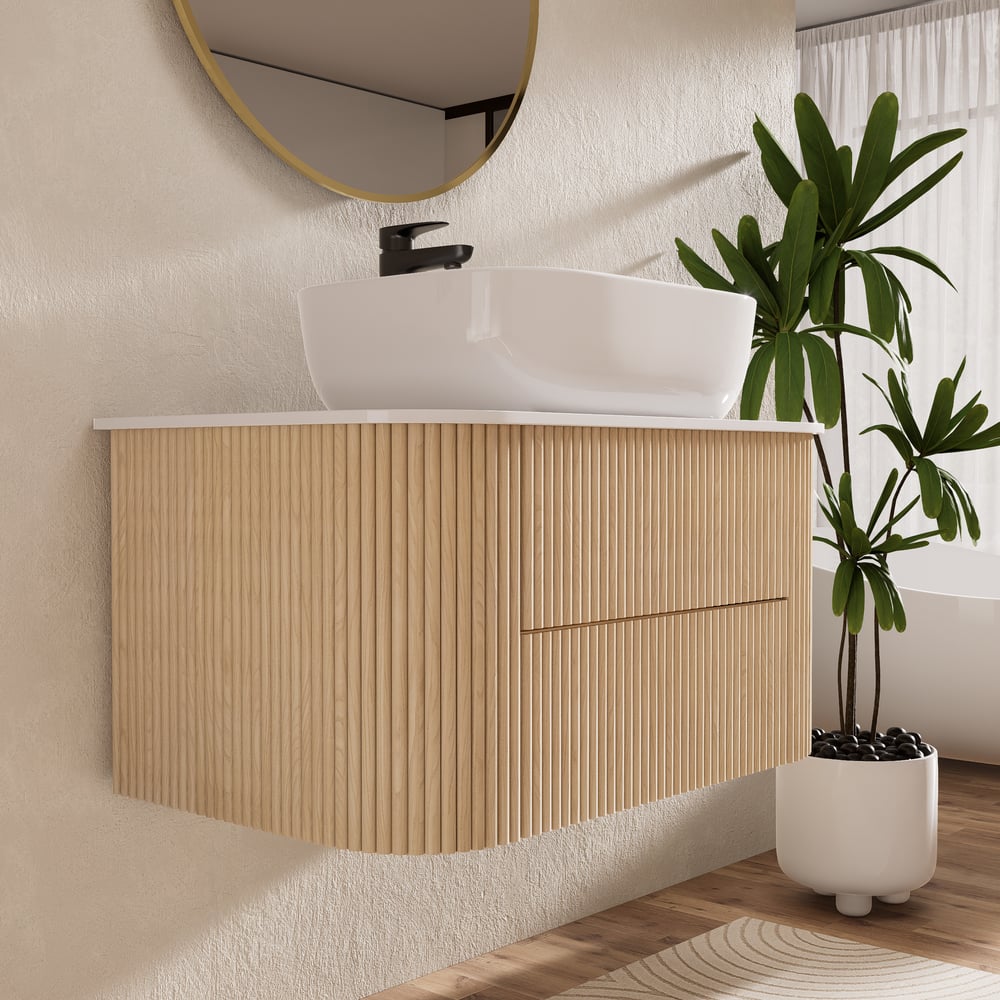Bathroom vanity with wooden cabinet, white sink, and plant in a modern setting.