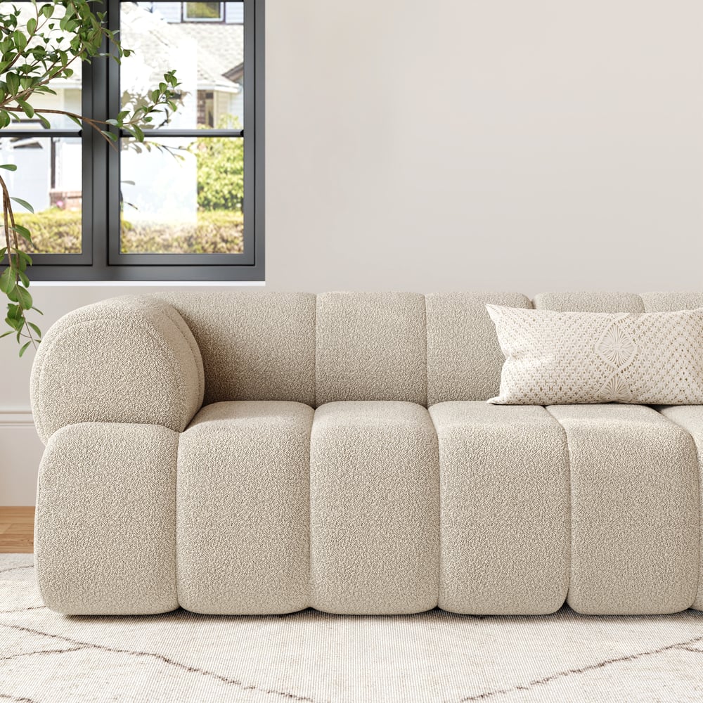 Beige textured sofa in a living room with a window and plants.