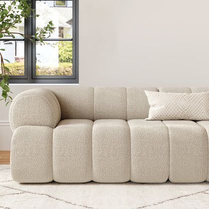 Beige textured sofa in a living room with a window and plants.