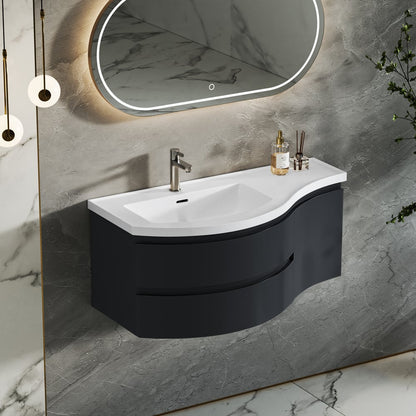 Bathroom vanity with white sink and black cabinet against a marble wall.