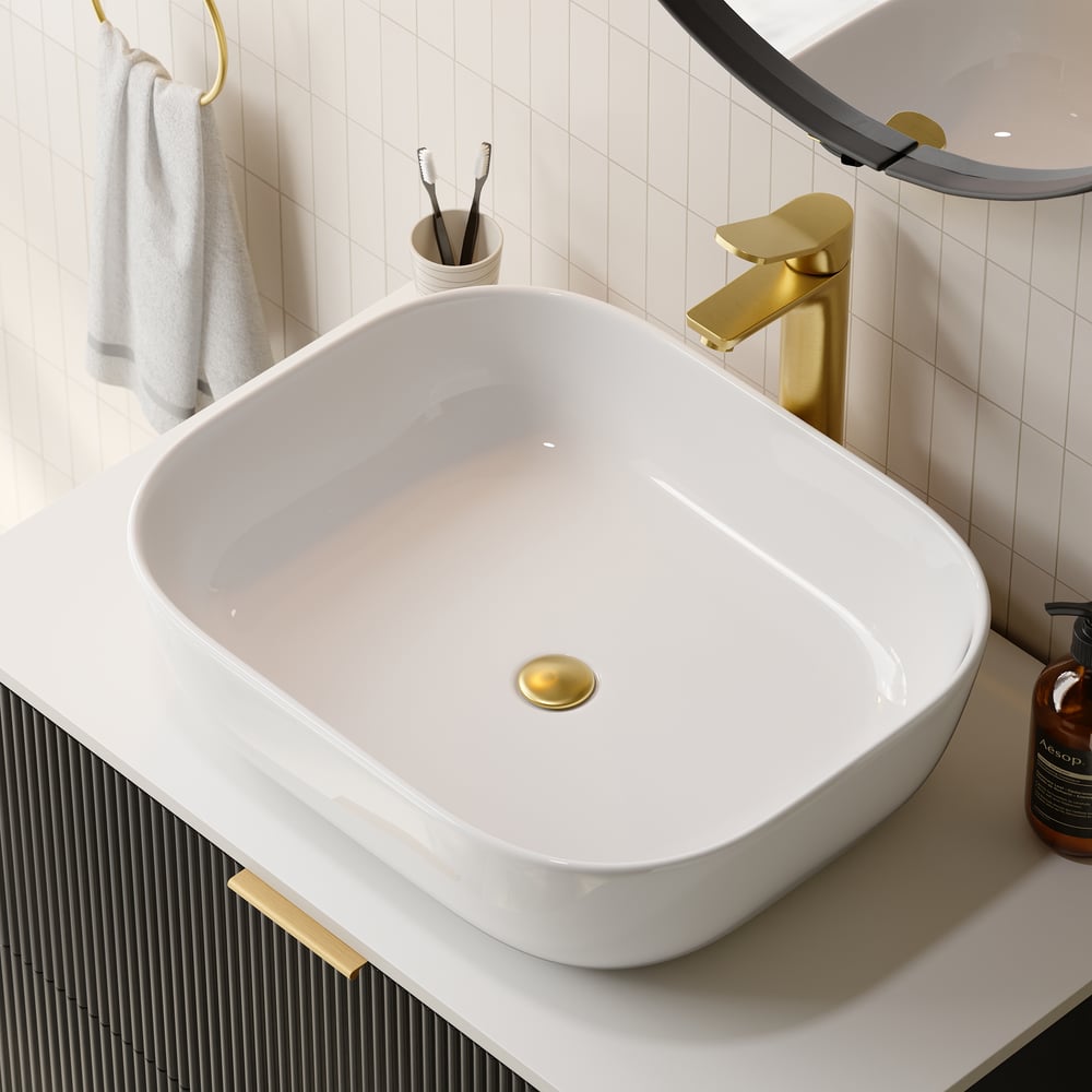 White sink with gold faucet and decorative elements in a bathroom setting