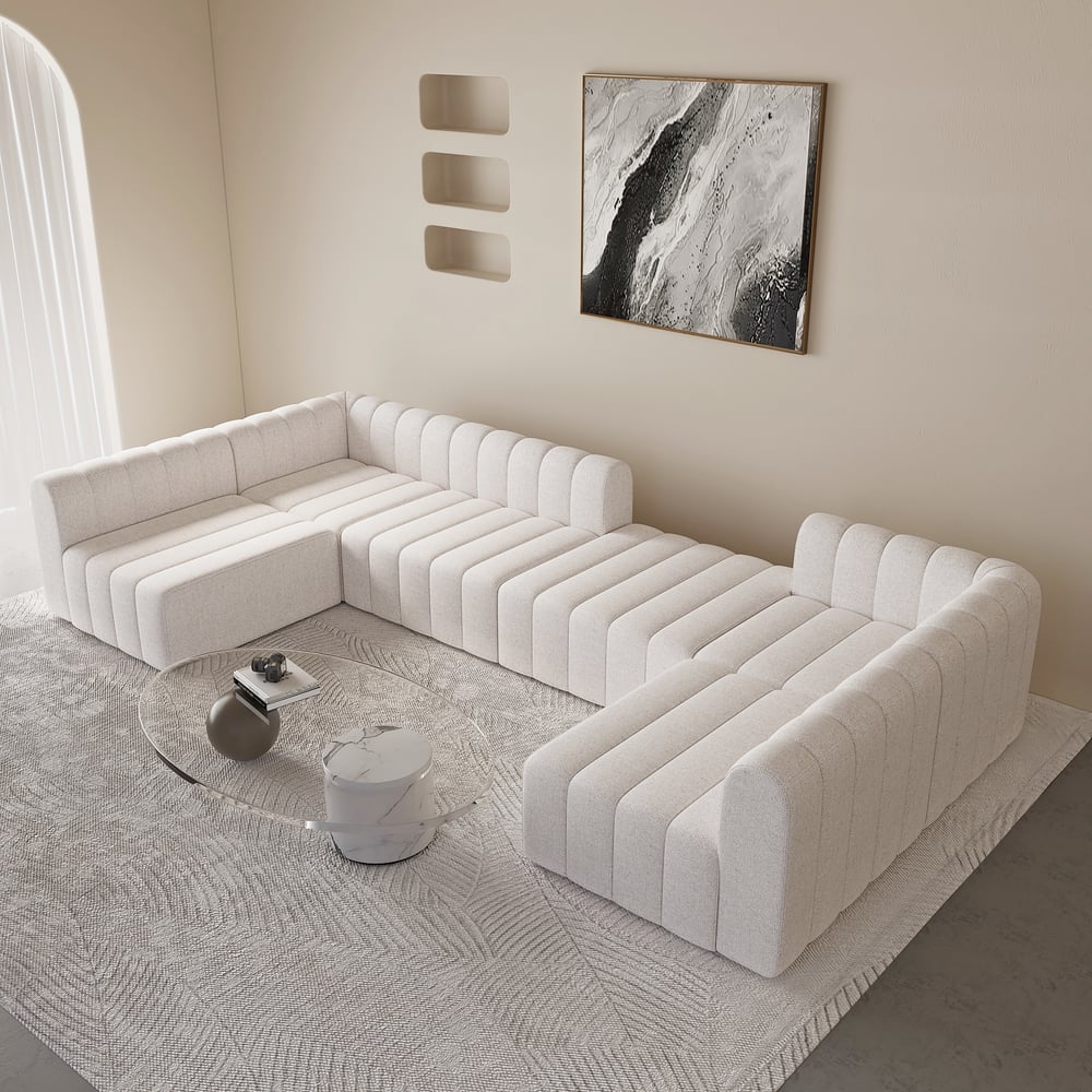 Modern living room with a white sectional sofa, coffee table, and abstract art on the wall.