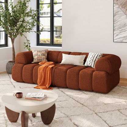 Brown sofa with cushions and a blanket in a living room setting.
