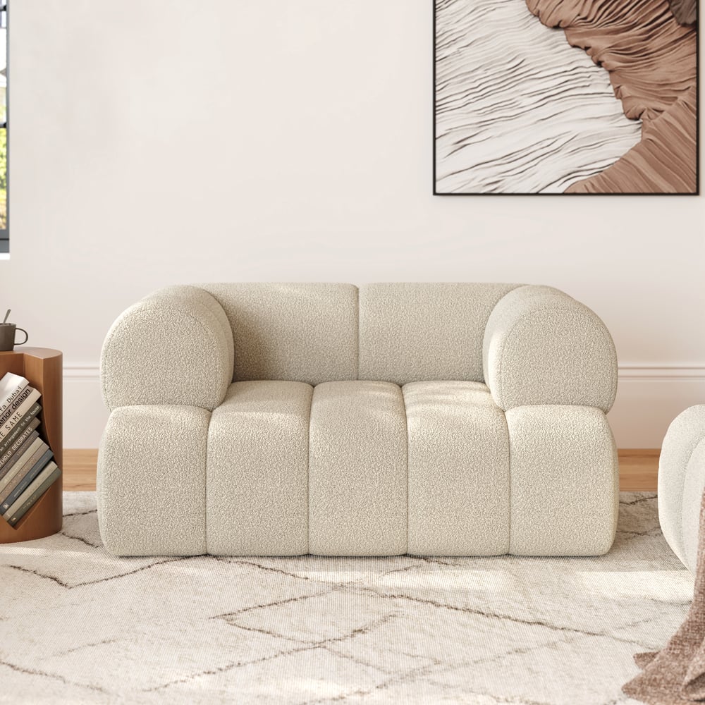 Beige sofa in a living room setting with a textured wall and abstract art.