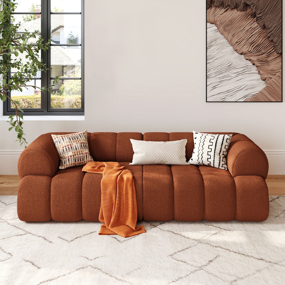 Brown sofa with decorative pillows and a blanket in a living room setting.