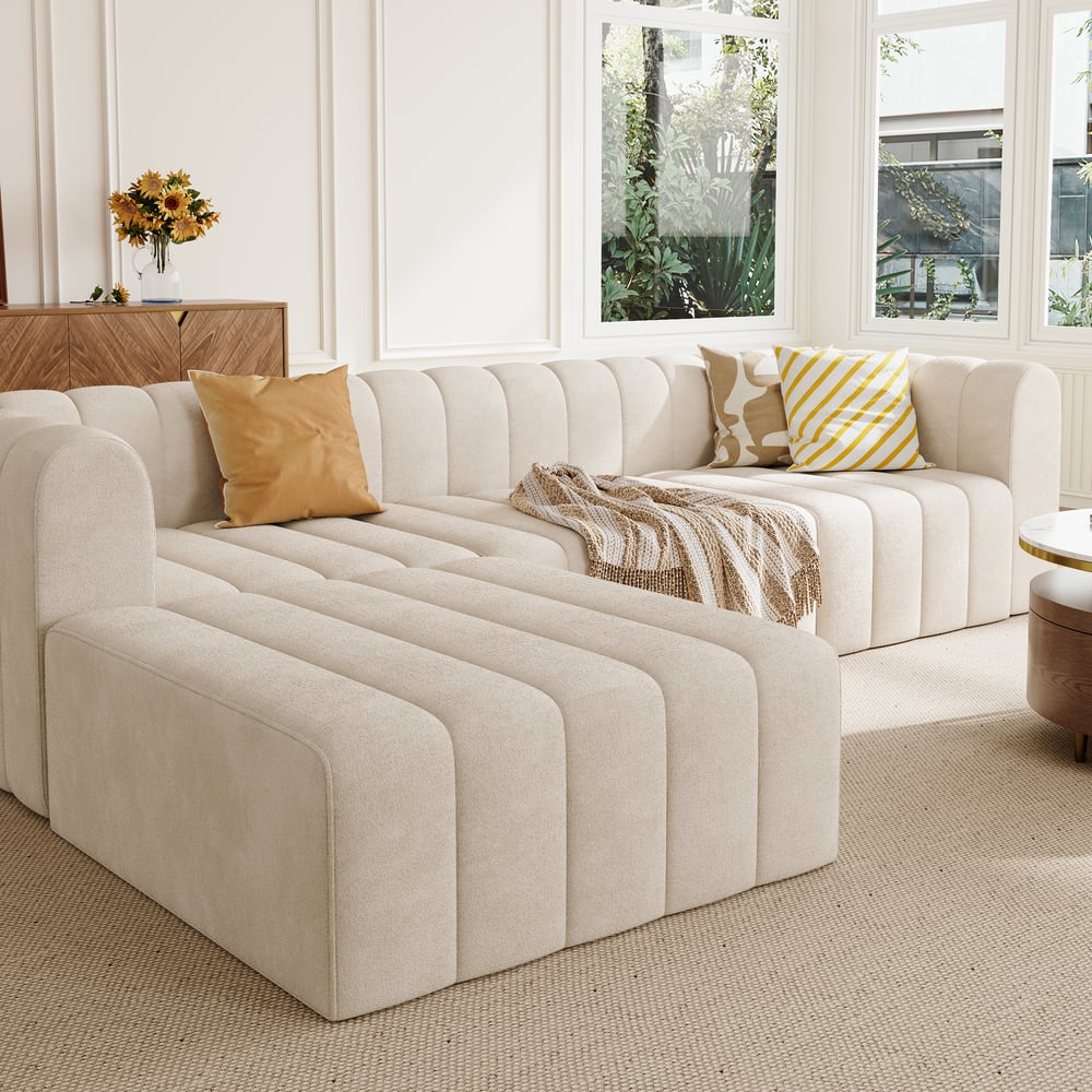 Off white sectional sofa with decorative pillows and a blanket in a bright living room.