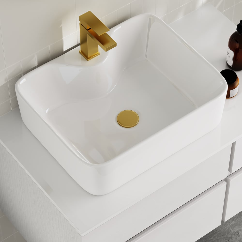 White sink with gold faucet and drain in a bathroom setting