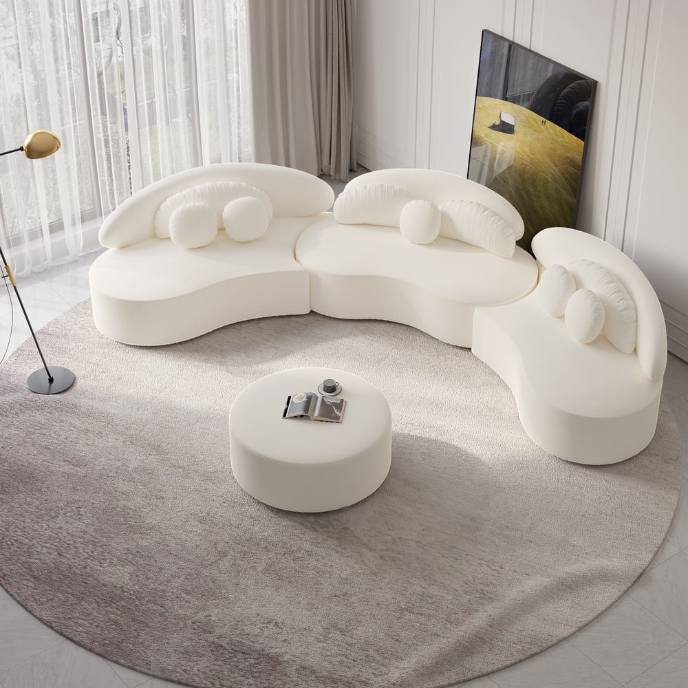 Modern white sofa with a round ottoman on a gray rug in a room with curtains and a painting.