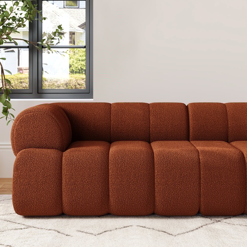 Brown textured sectional sofa in a room with a window and plants.