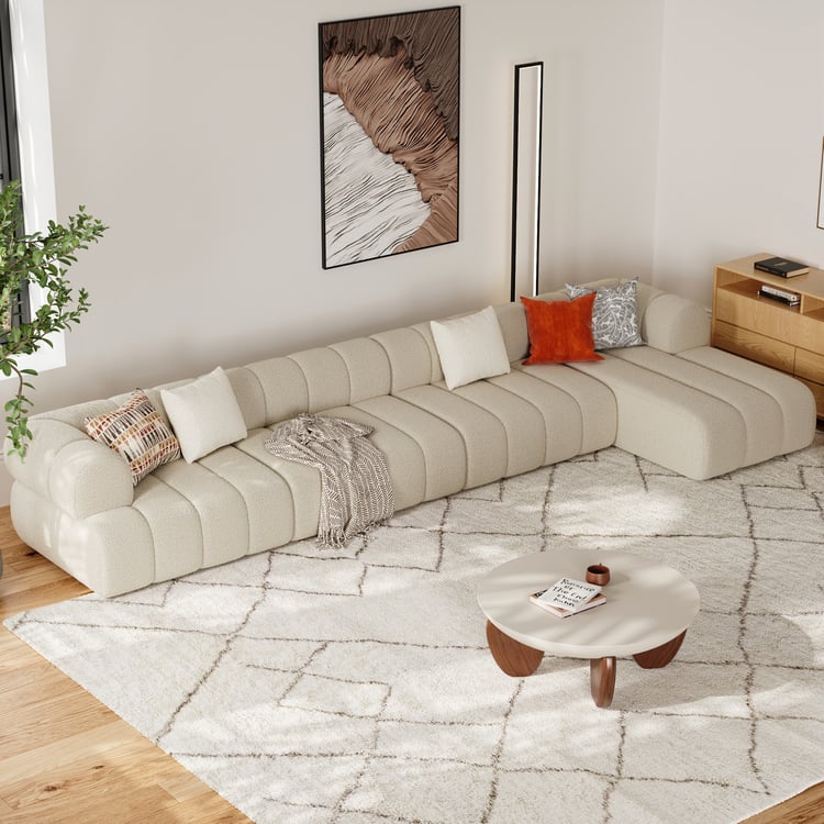 Modern living room with a beige sectional sofa, coffee table, and decorative pillows.