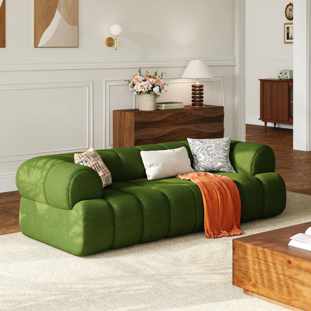 Green sofa with decorative pillows and a blanket in a living room setting.