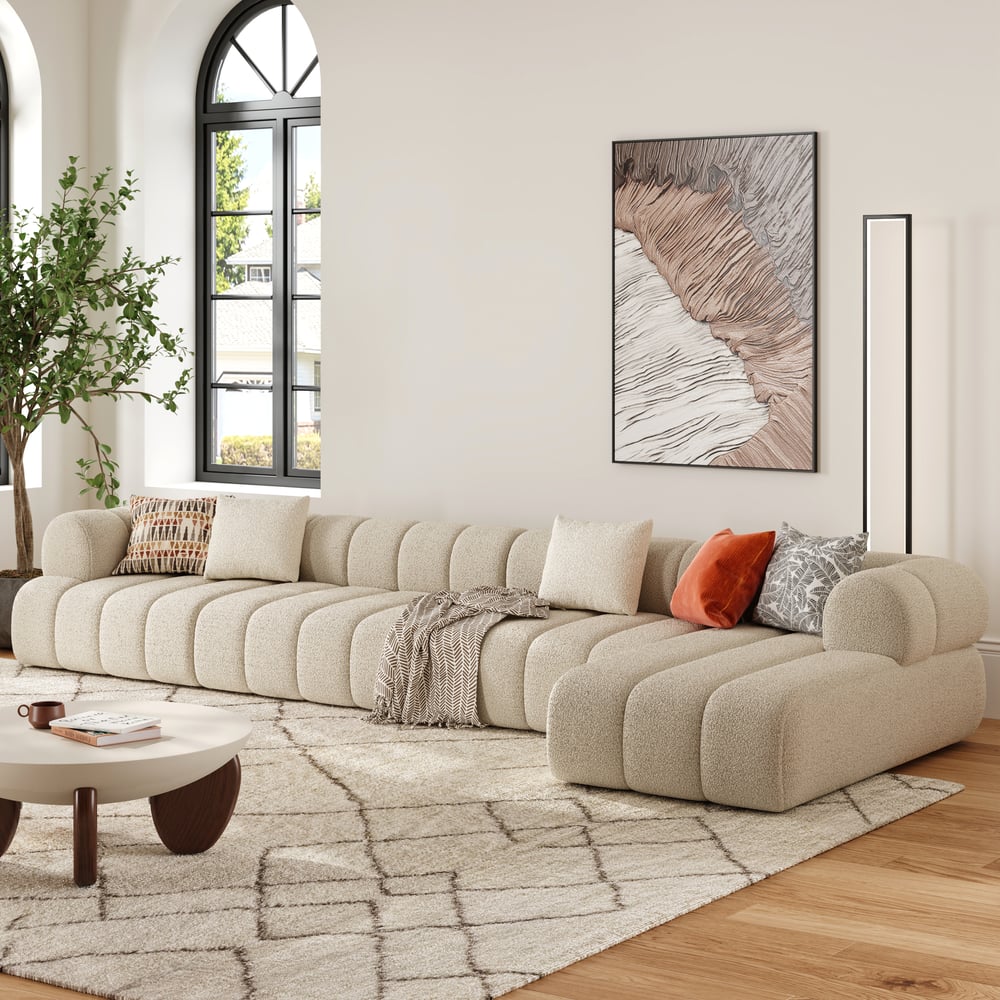 Beige sectional sofa in a living room with a coffee table, rug, and wall art.