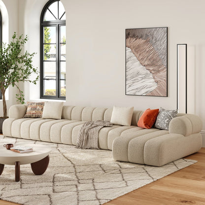 Beige sectional sofa in a living room with a coffee table, rug, and wall art.