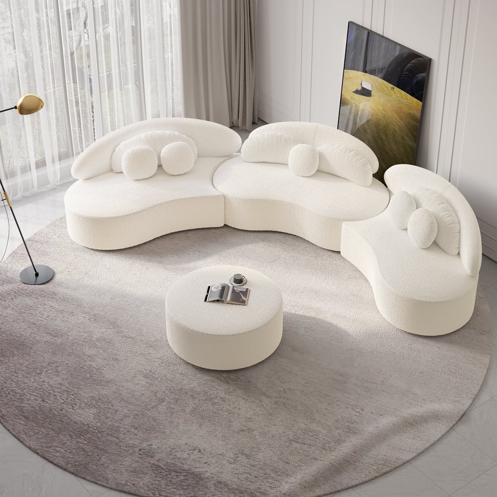 Modern white sectional sofa with a round ottoman on a gray rug.