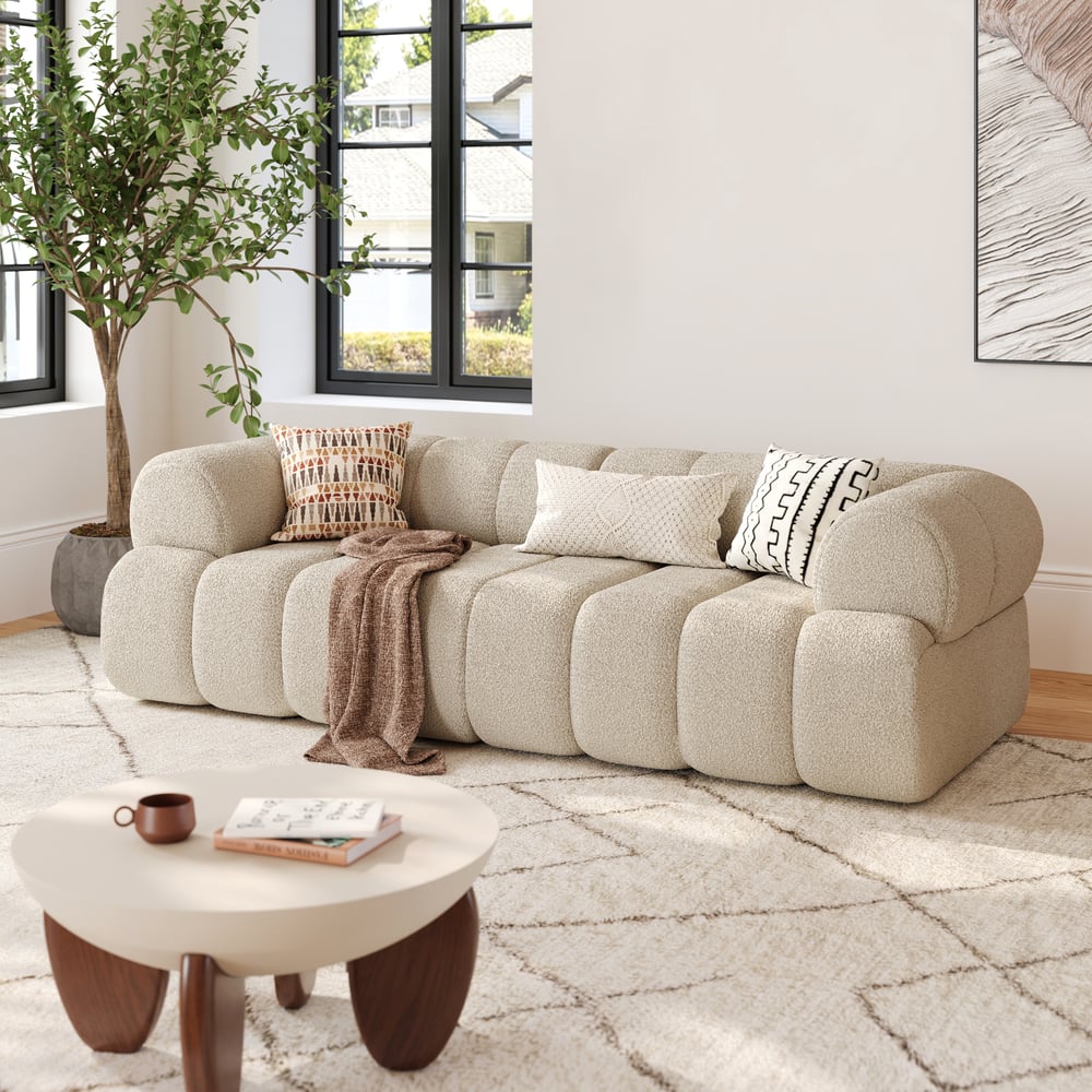 Beige sectional sofa in a living room with a coffee table and decorative items.