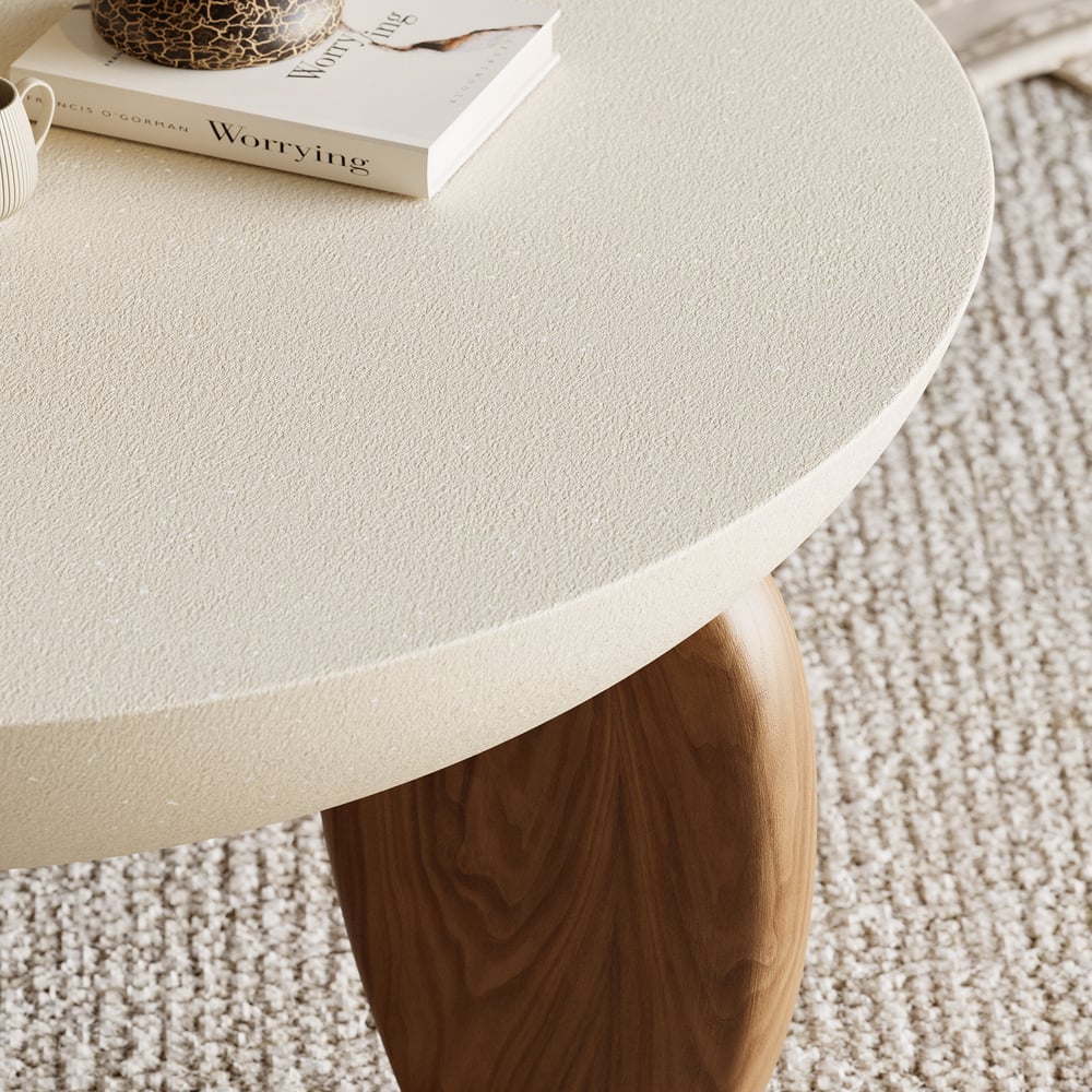 Round beige table with a wooden leg on a textured carpet
