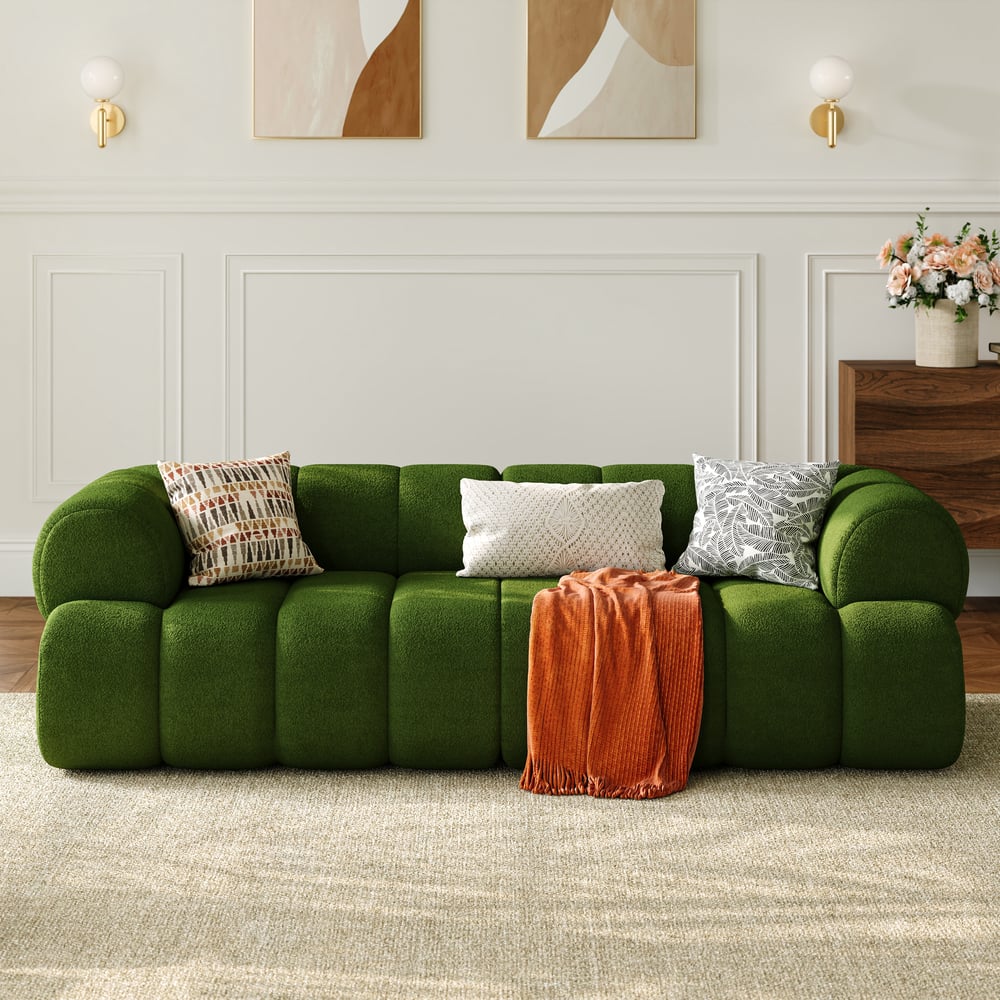 Green sofa with decorative pillows and a blanket in a living room setting.