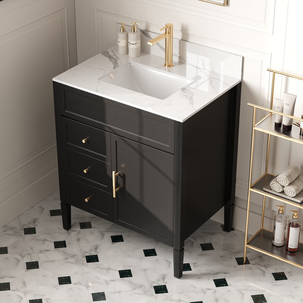 Bathroom vanity with white countertop, gold fixtures, and black floor tiles.