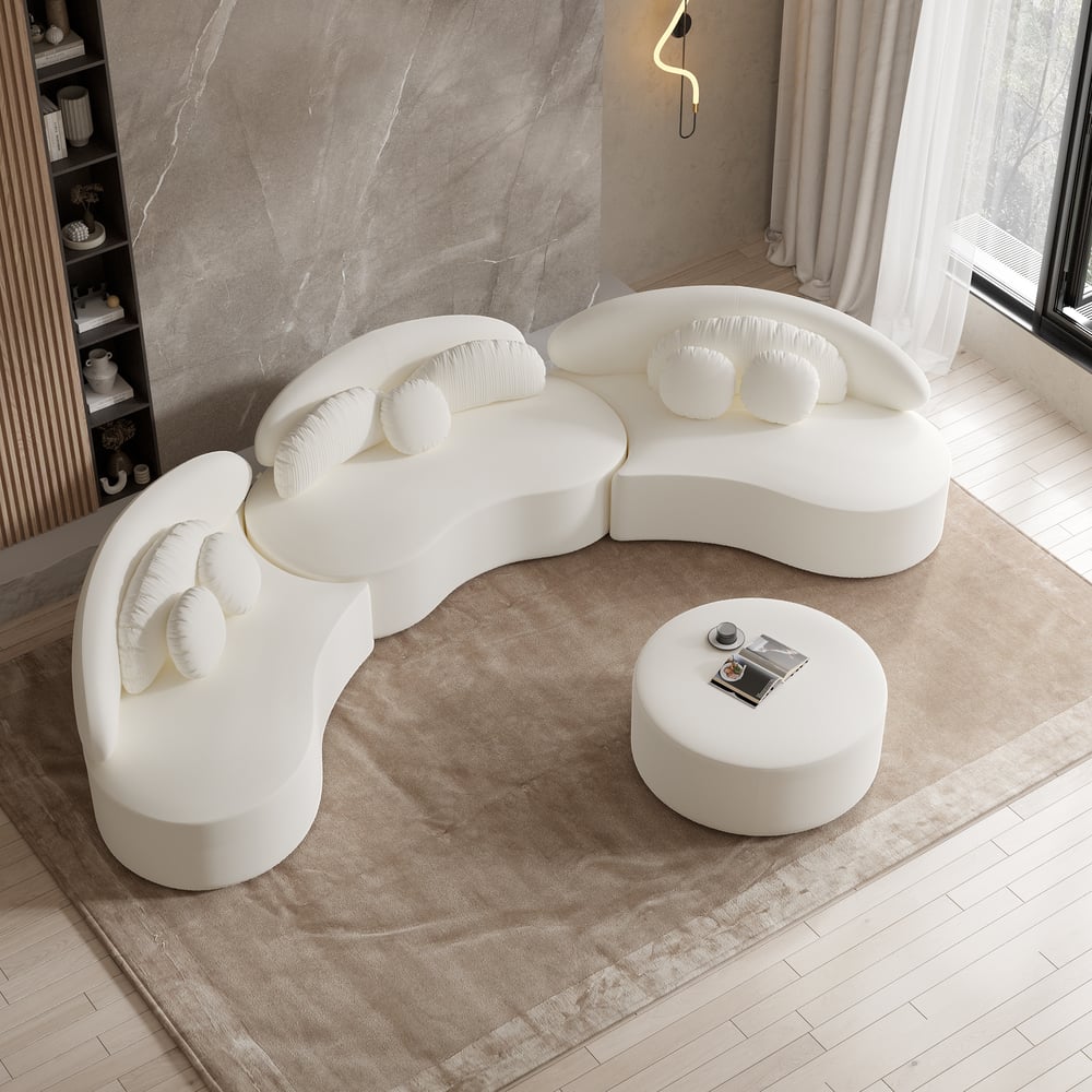Modern white sofa with a round ottoman in a minimalistic room.