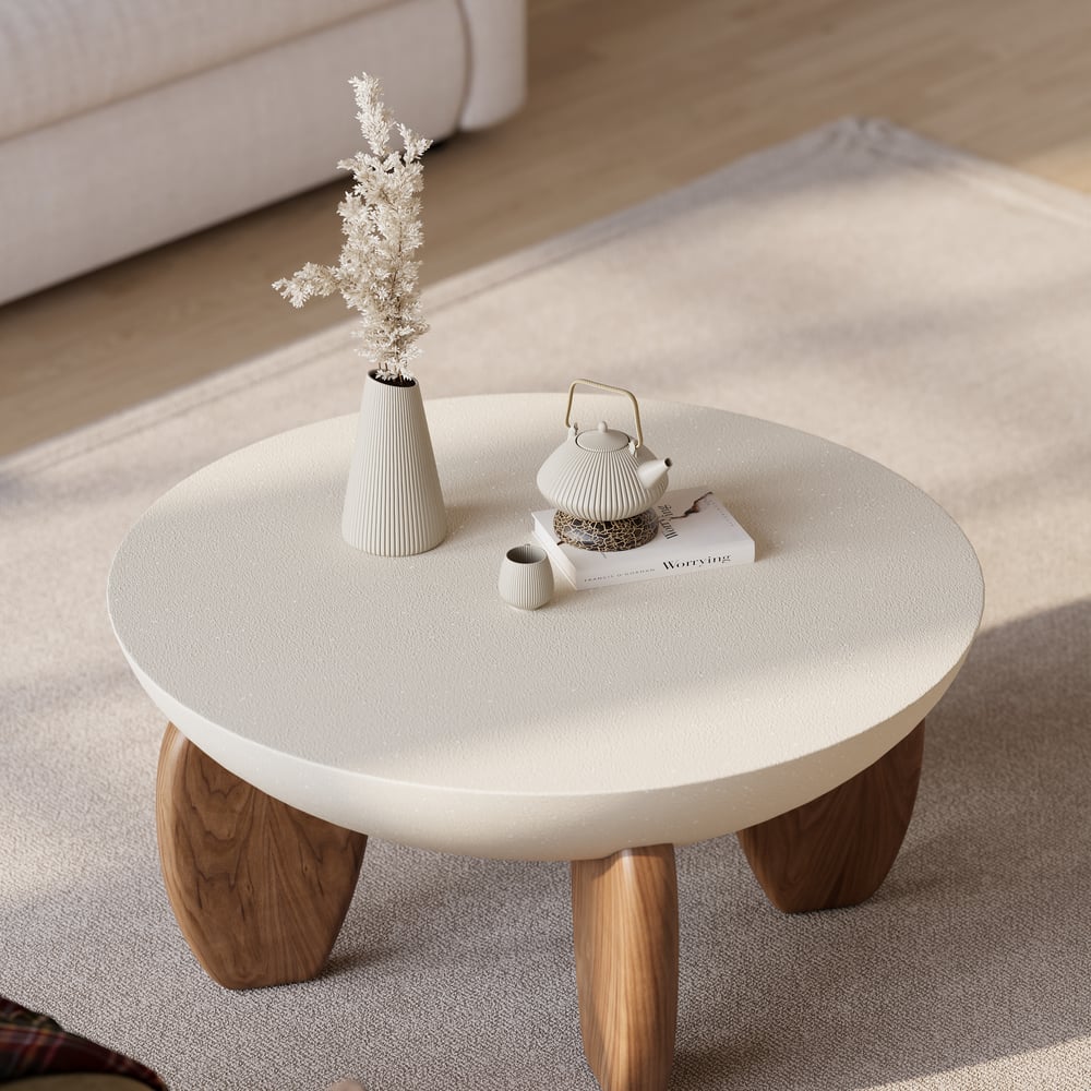 Round coffee table with wooden legs in a living room setting
