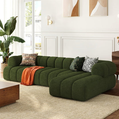 Green sectional sofa in a living room with decorative pillows and a plant.