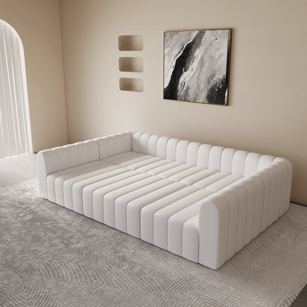 White tufted sofa in a minimalistic room with abstract art on the wall.